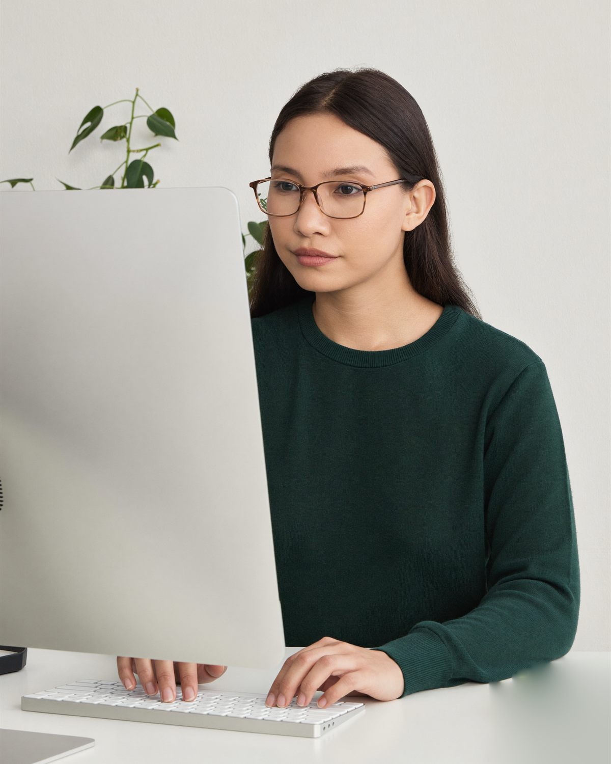 A medical coder VA in glasses typing at her computer