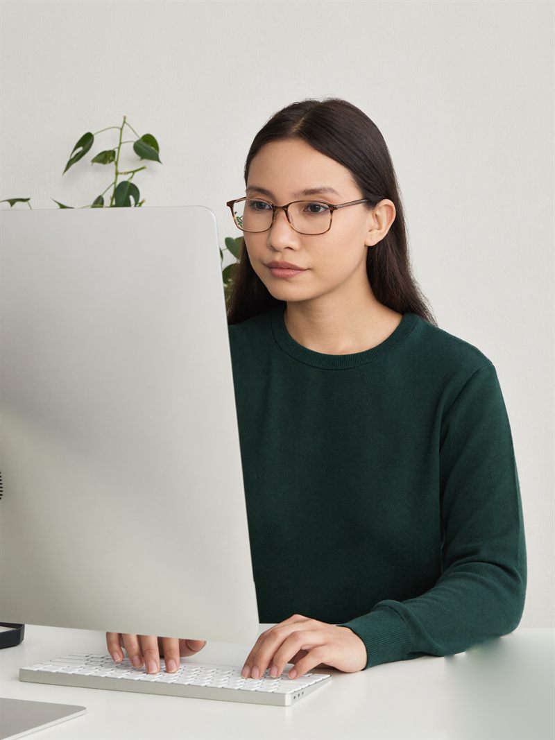 A medical coder VA in glasses typing at her computer