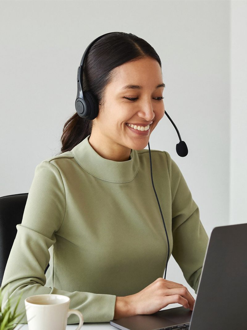 A medical receptionist VA in a headset smiling on a patient call
