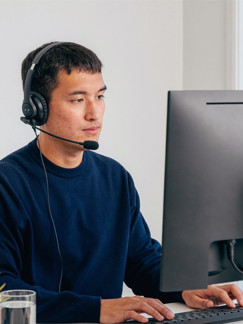 A medical scribe VA in a headset typing at his computer