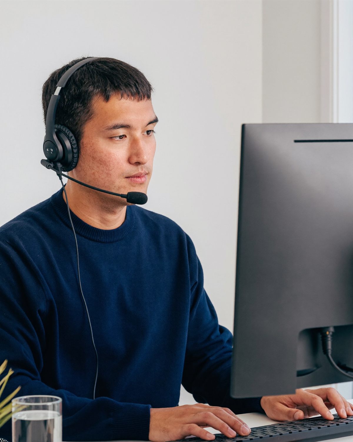A medical scribe VA in a headset typing at his computer